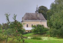 Venkovský kostel na kopci mezi stromy a zahradou