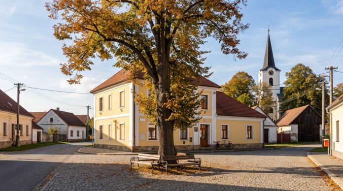 Budova obecního úřadu malé obce na návsi s lípou a kostelem Budova obecního úřadu malé obce na návsi s lípou a kostelem