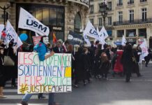 Demonstrace v ulicích Paříže s transparenty a vlajkami odborů
