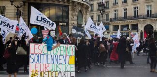 Demonstrace v ulicích Paříže s transparenty a vlajkami odborů