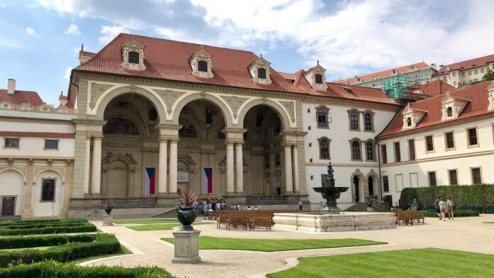 Sala terrena Valdštejnského paláce v Praze, sídla Senátu, s českými vlajkami a kašnou v zahradě